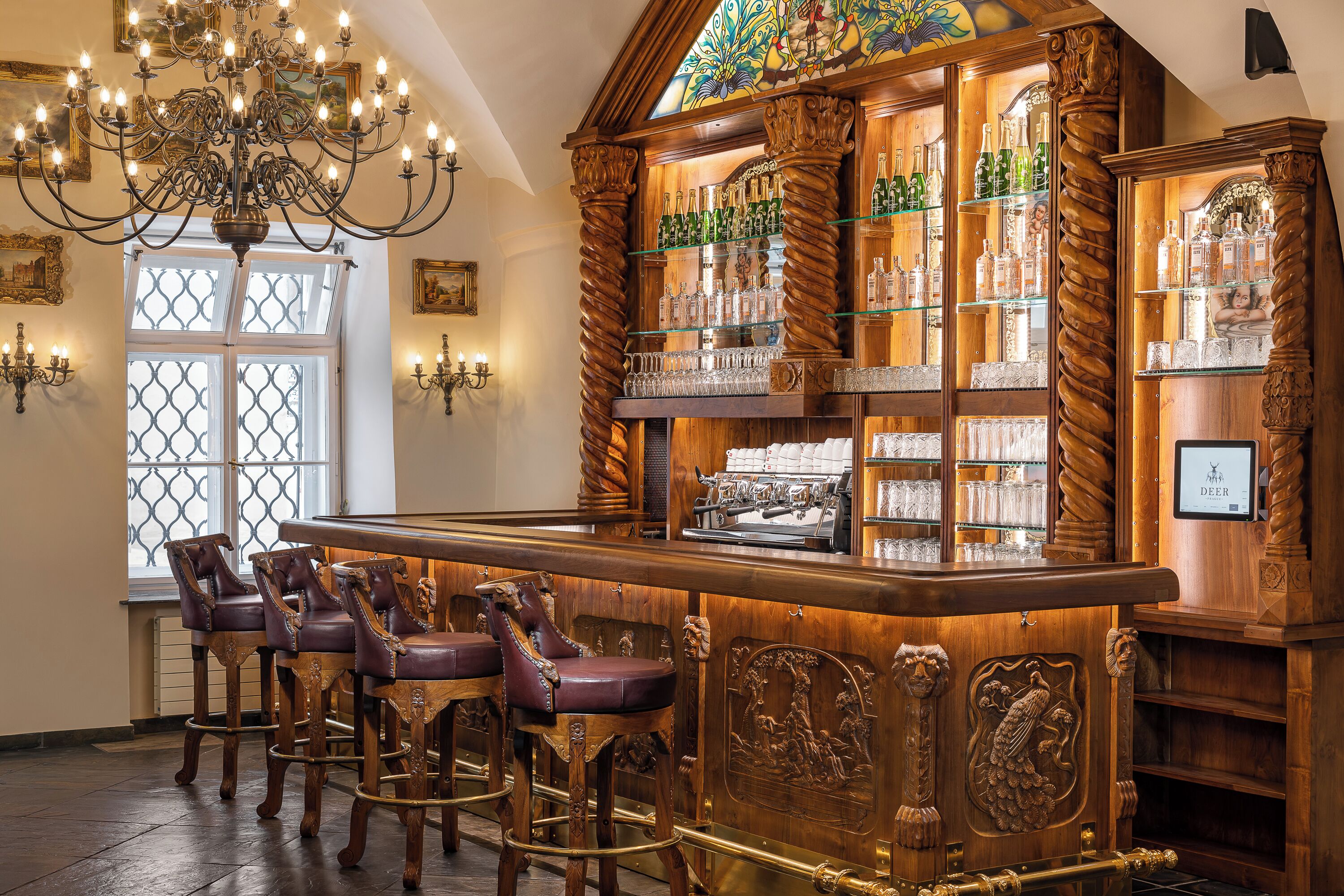 Un espace bar avec des tabourets de bar en bois, un comptoir et des étagères remplies de bouteilles.