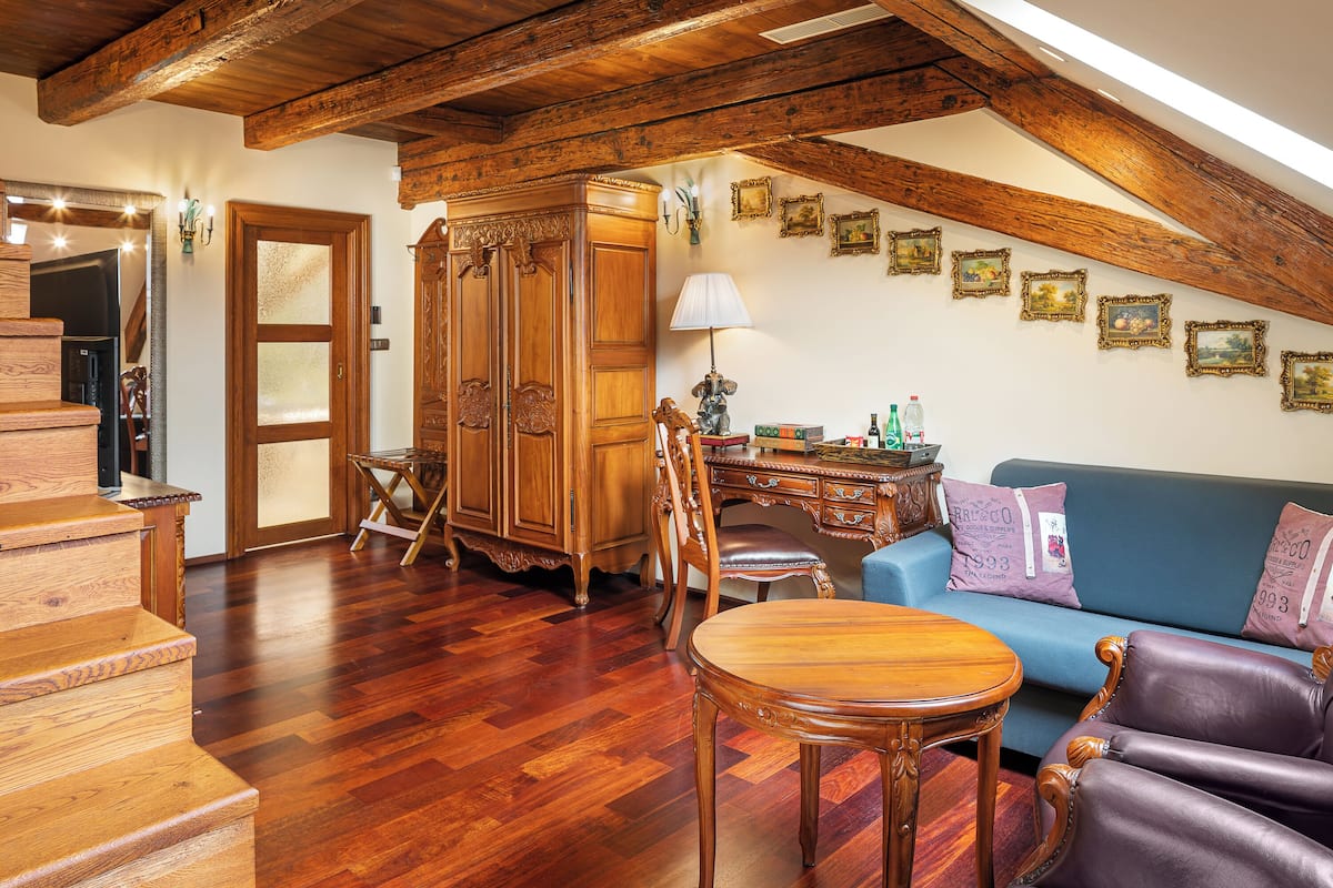 Amplia sala de estar con una escalera de madera, un sofá azul, una mesa de comedor de madera y un armario de madera.