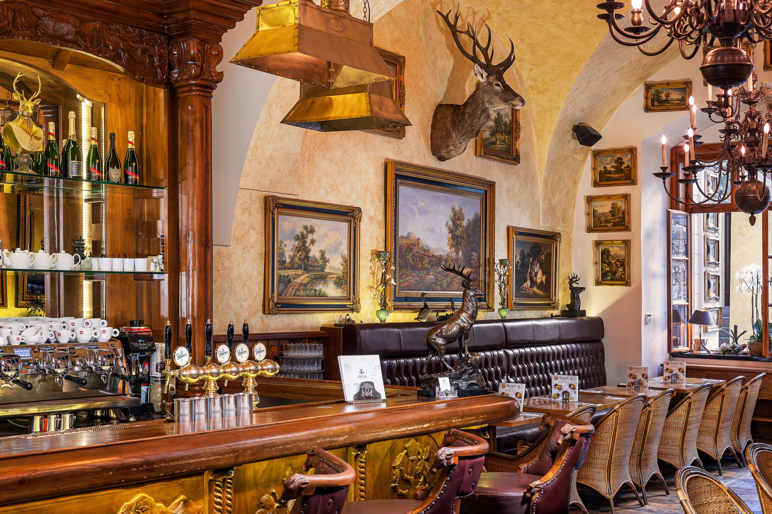 Una zona de bar con mostrador de madera, varias llaves de cerveza y un asiento de cuero tipo banqueta.