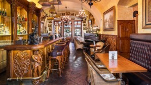 Una zona de bar con mostradores de madera, asientos de cuero y candelabros.