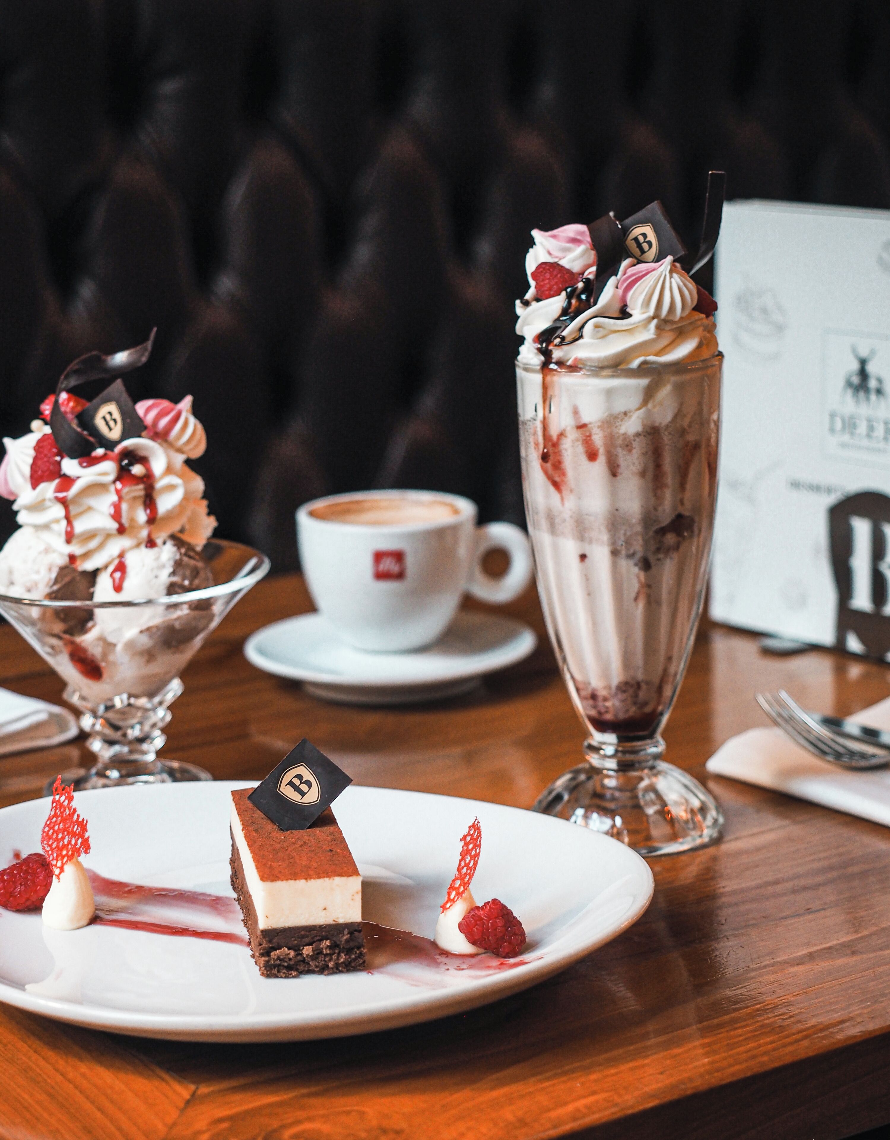 A dessert table with a chocolate cake, a sundae, and a cup of coffee.