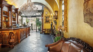 Un vestíbulo imponente con un mostrador de recepción de madera, un candelabro y un banco de cuero.