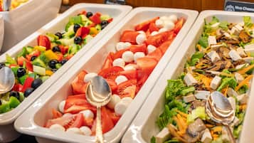 A buffet with various salads including a tomato and mozzarella salad, a mixed vegetable salad, and a salad with tofu and mushrooms.