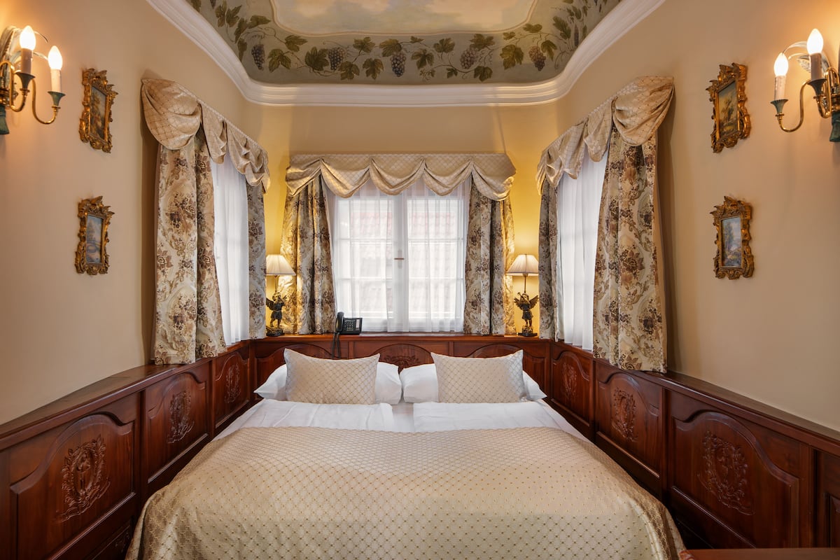 Una cama grande con cabecera de madera, dos lámparas de noche y cortinas con estampado floral.