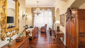 Amplia habitación con un espejo grande y ornamentado, un candelabro y una mesa de comedor de madera con sillas.