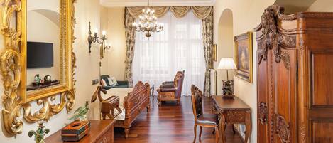 Amplia habitación con un espejo grande y ornamentado, un candelabro y una mesa de comedor de madera con sillas.