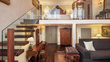 A spacious living area with a staircase, a sofa, a dining table, and a chandelier.