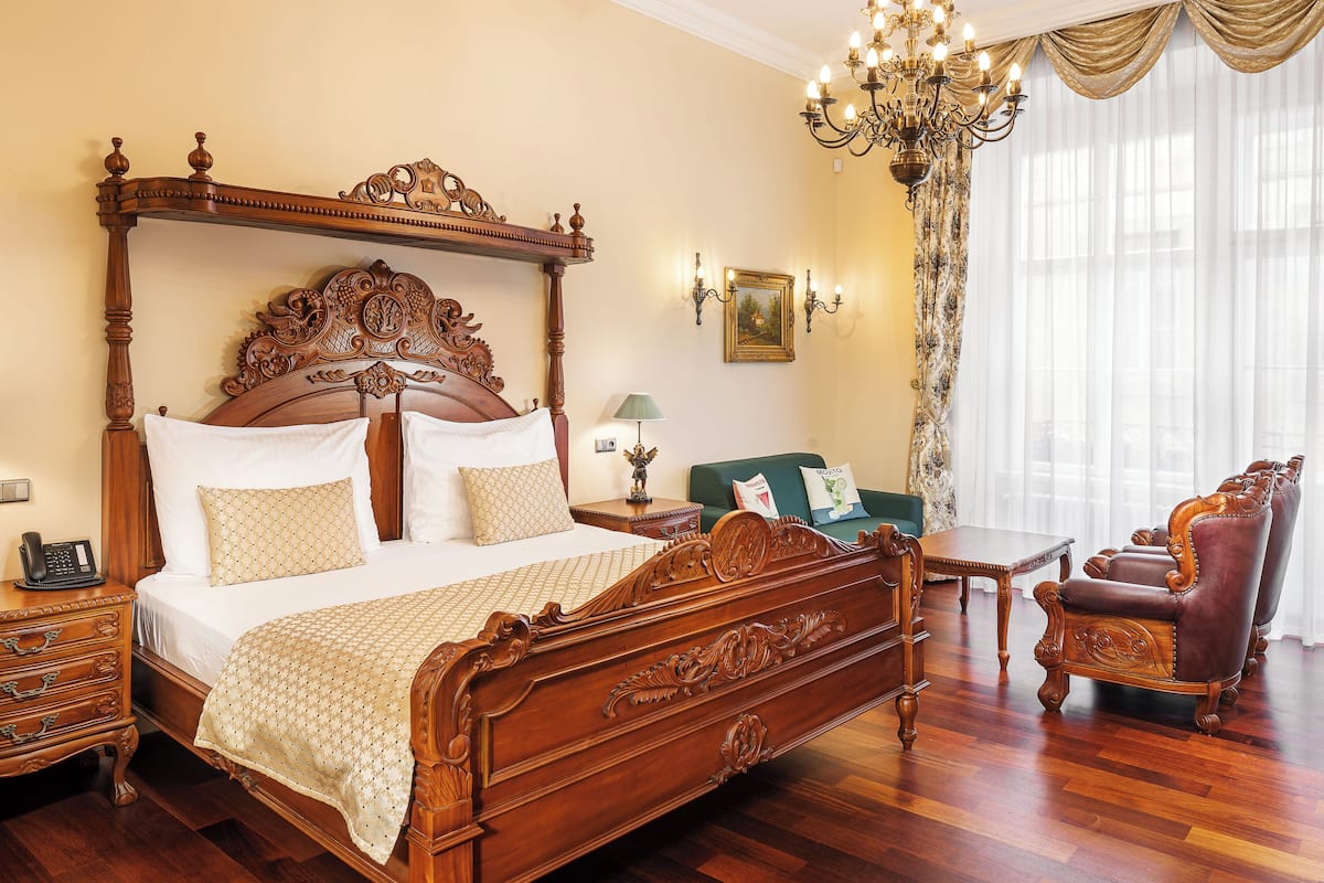 Un dormitorio amplio con una cama grande de madera, una silla de madera clásica y un sofá verde.