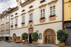 Un edificio storico con ristorante al piano terra, caratterizzato da una facciata classica, finestre ad arco e piante in vaso.