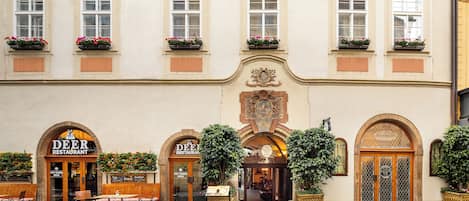 A building with multiple windows, a central entrance with an arch, and outdoor seating.