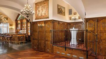 Un'ampia stanza con pannelli in legno, un angolo bar con sgabelli e una scala che conduce a un piano superiore.