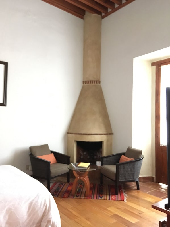 A room with a fireplace, two armchairs, a small table, and a bed. - Quinta Luna (San Pedro Cholula)