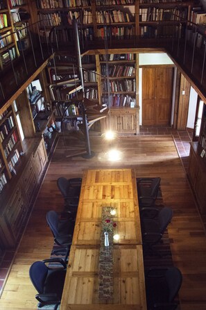 A spacious library with wooden bookshelves, a central wooden table, and multiple seating areas. - Quinta Luna (San Pedro Cholula)