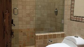 A bathroom with a shower, toilet, and a mirror.