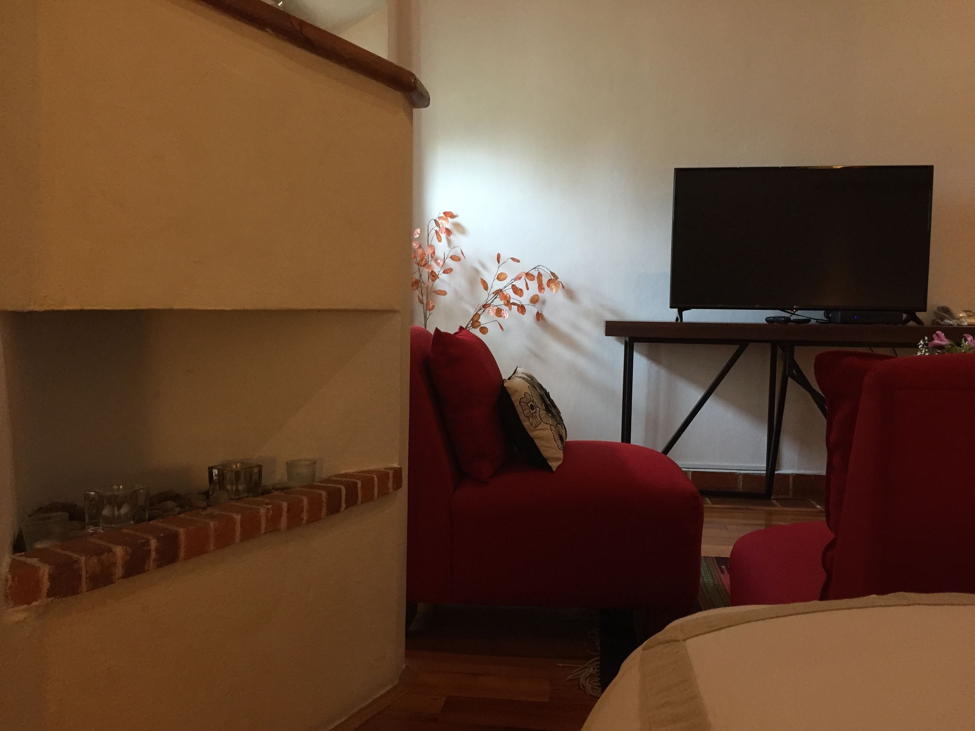 A room with a fireplace, a television on a stand, and a red chair.