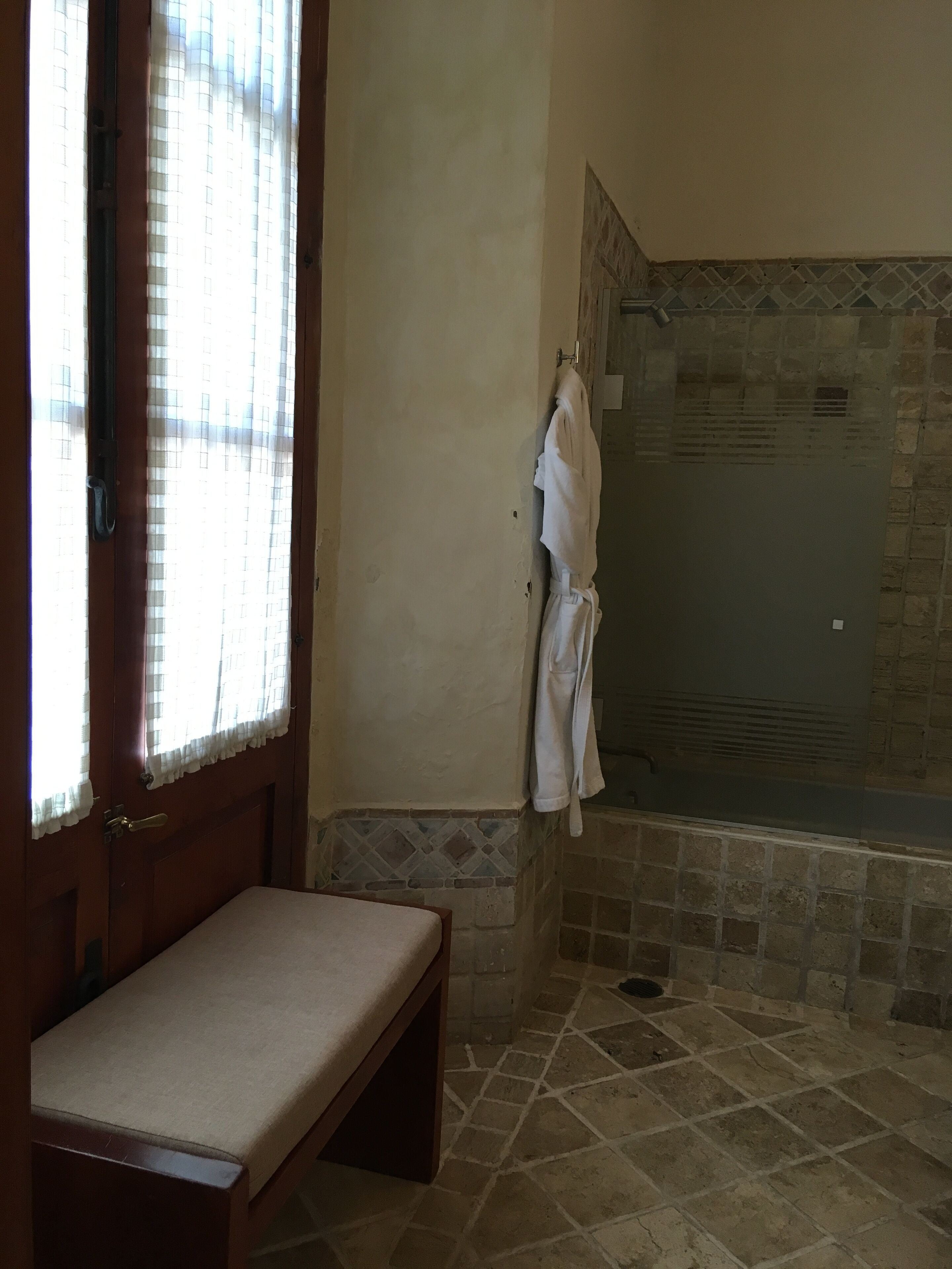 Un baño con bañera, un banco y un perchero para toallas.