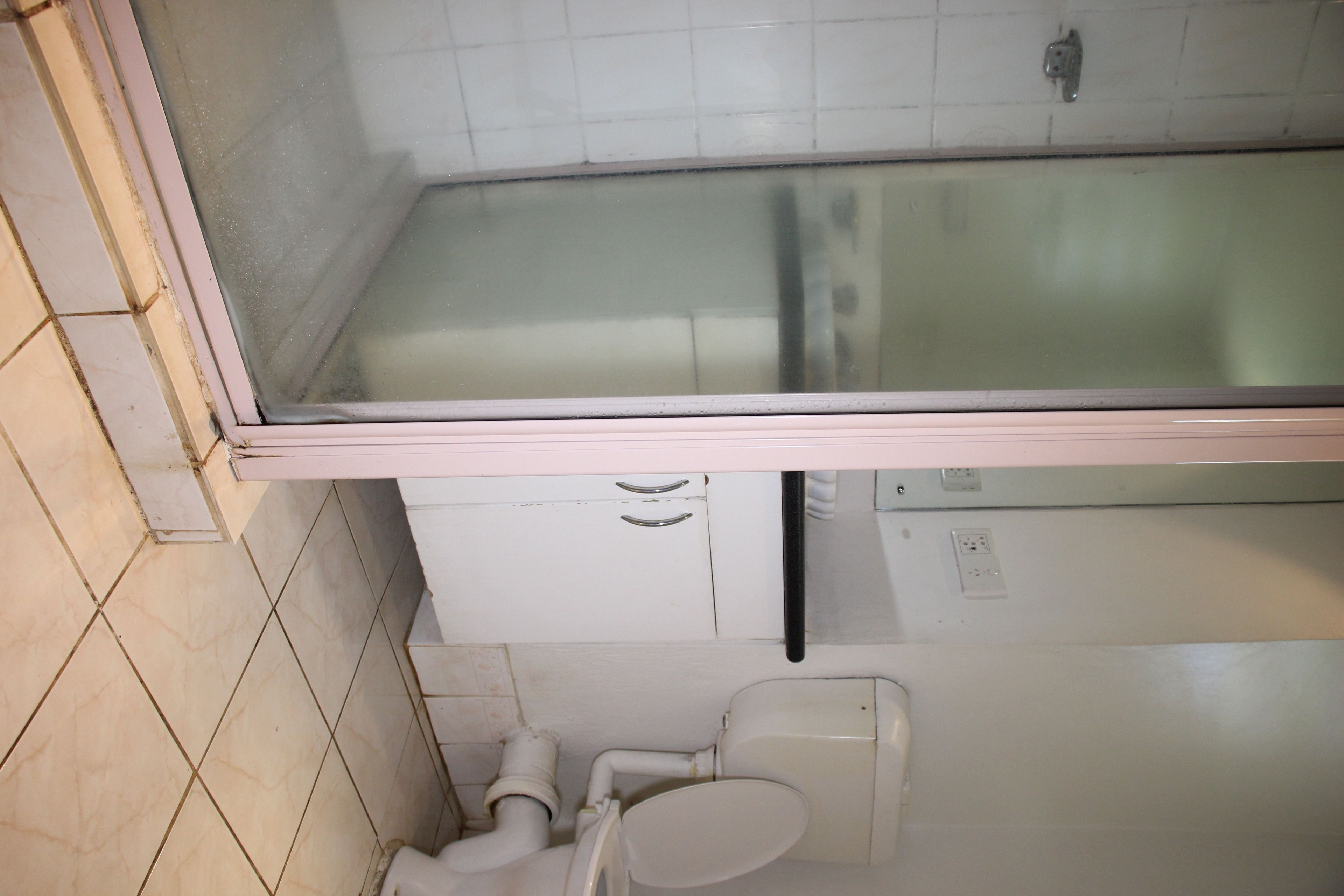A bathroom with a glass-enclosed shower, a toilet, and a sink.