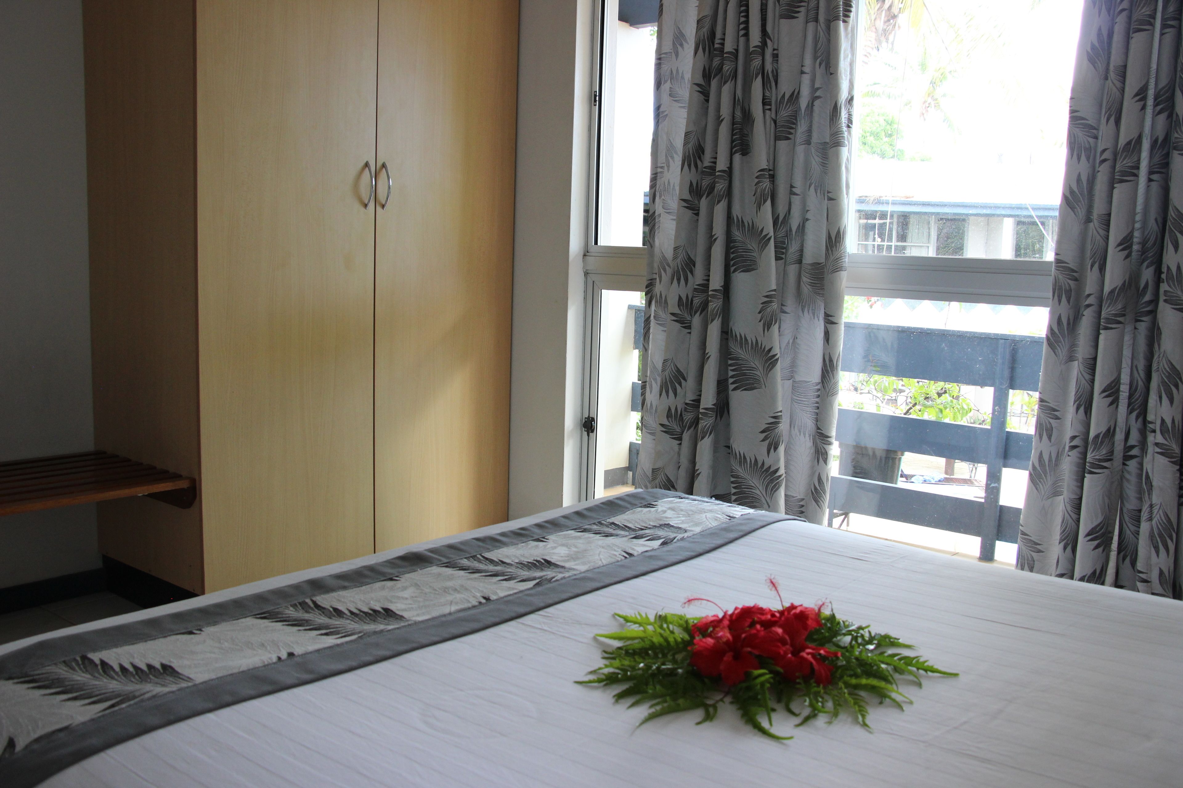 Une chambre d’hôtel avec un lit, une armoire en bois et une fenêtre avec des rideaux.