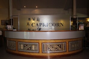 Balcão de recepção com o nome "CAPRICORN" e padrões decorativos.