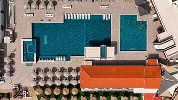 Vue aérienne d’un hôtel doté de plusieurs piscines, de chaises longues et de parasols.