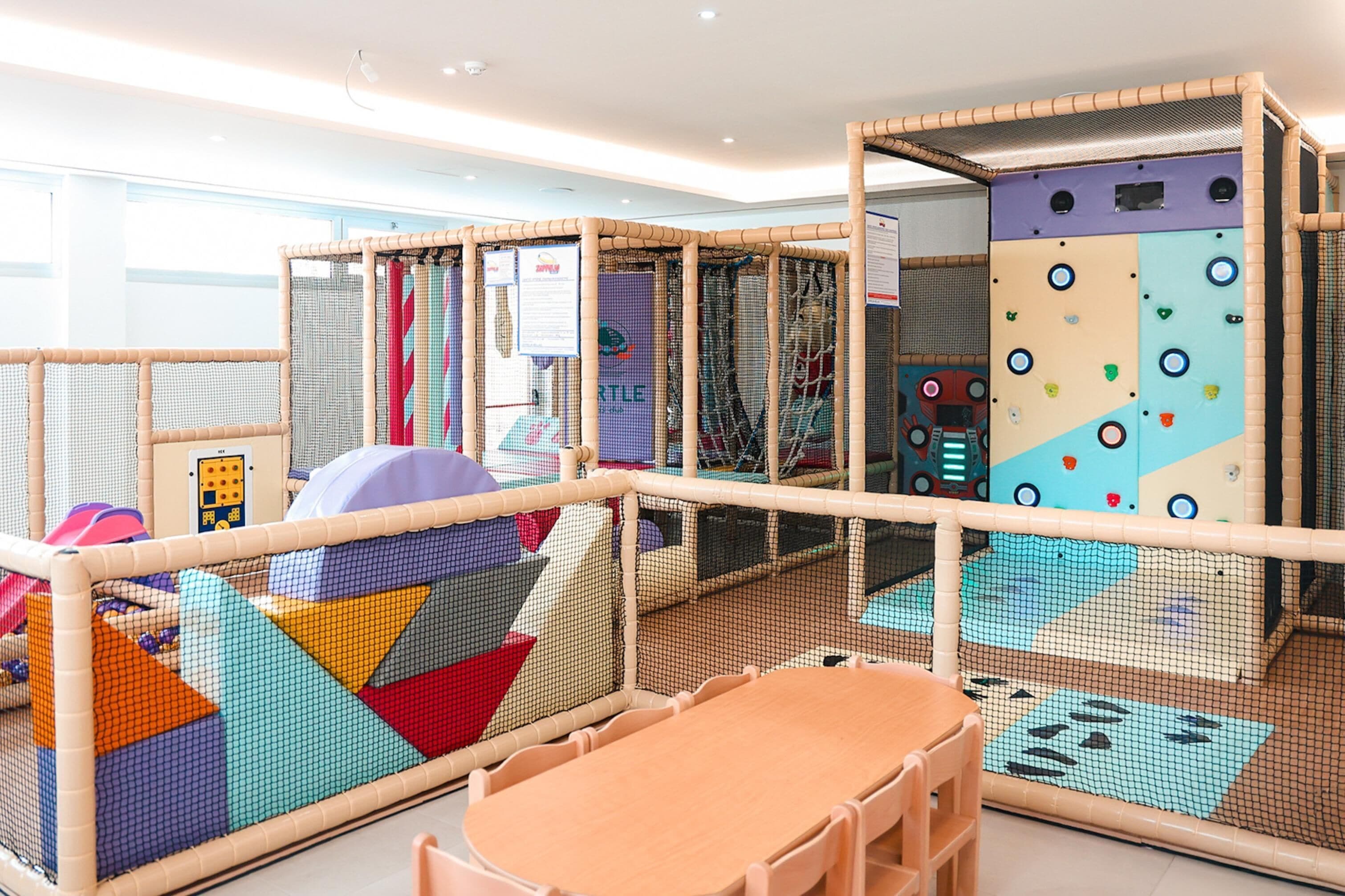 Un espace de jeux pour enfants avec des murs d’escalade, une table et des chaises.