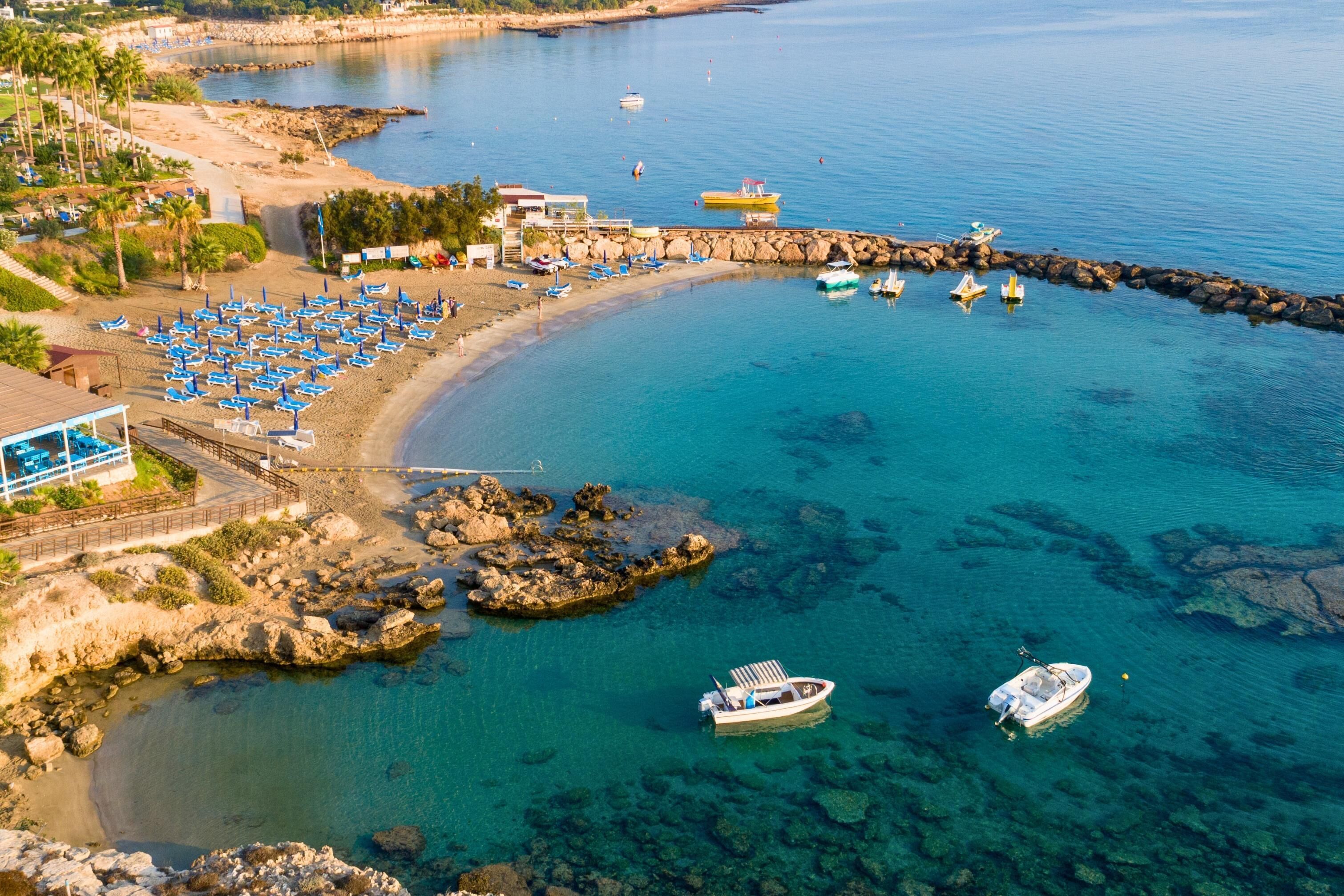 Una zona costera con aguas azul cristalino, una playa de arena y varios barcos.
