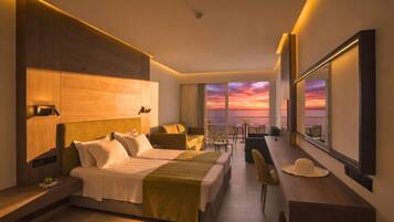 Habitación de hotel moderna con una cama grande, un escritorio, una silla y vistas a la puesta de sol a través de amplias ventanas.