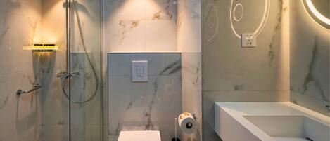 A modern bathroom with a glass-enclosed shower, a toilet, and a sink with a mirror.