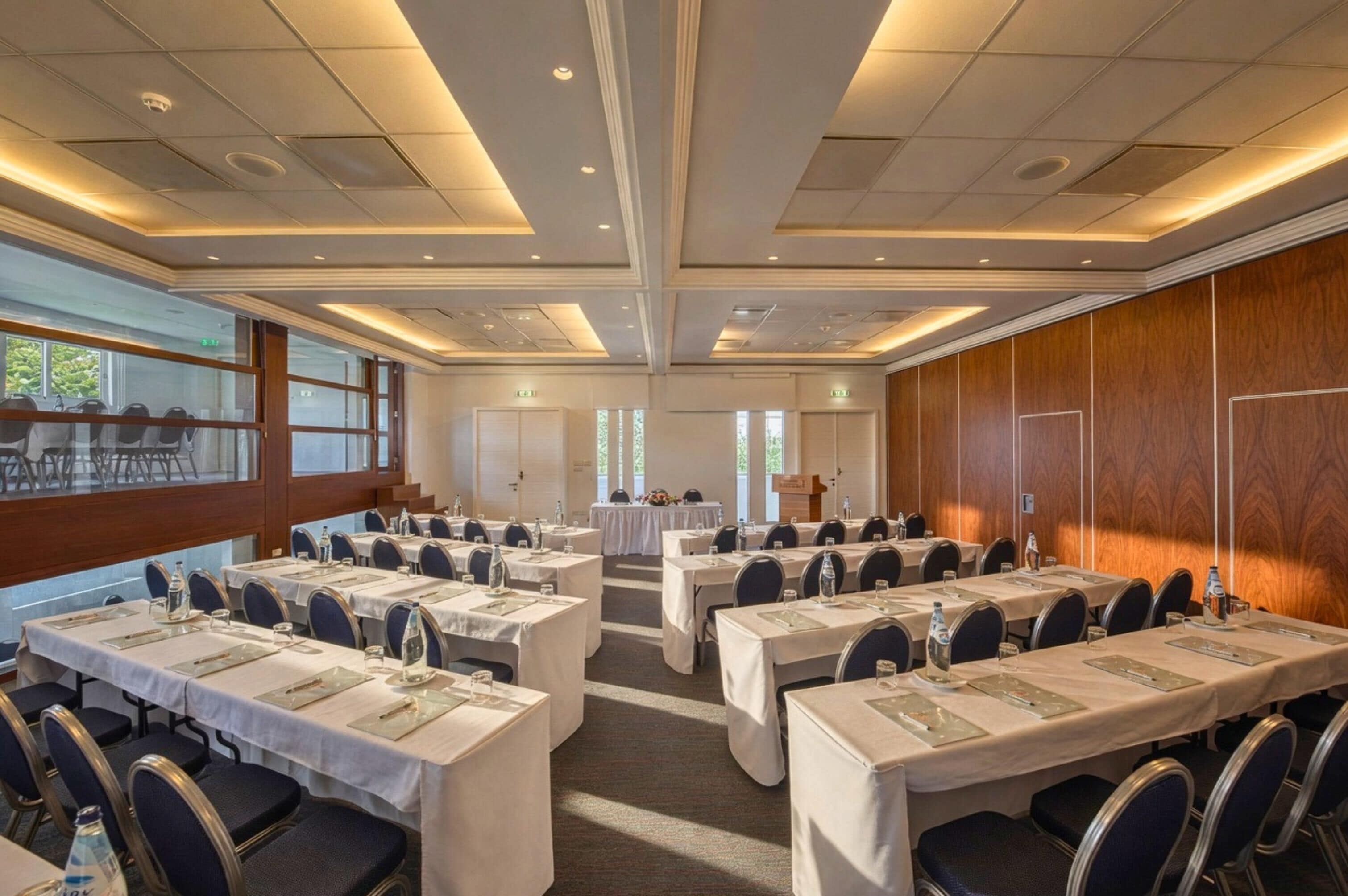 A conference room with multiple tables, chairs, and a podium.
