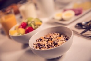 A breakfast setting with bowls of cereal and fruit, a glass of orange juice, and a plate with eggs. - Timhotel Paris Gare de Lyon (Paris)
