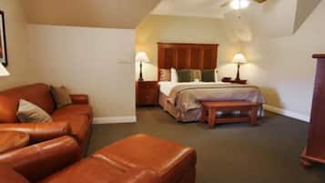 A bedroom with a bed, a wooden headboard, a nightstand, a lamp, a leather sofa, and a ceiling fan.