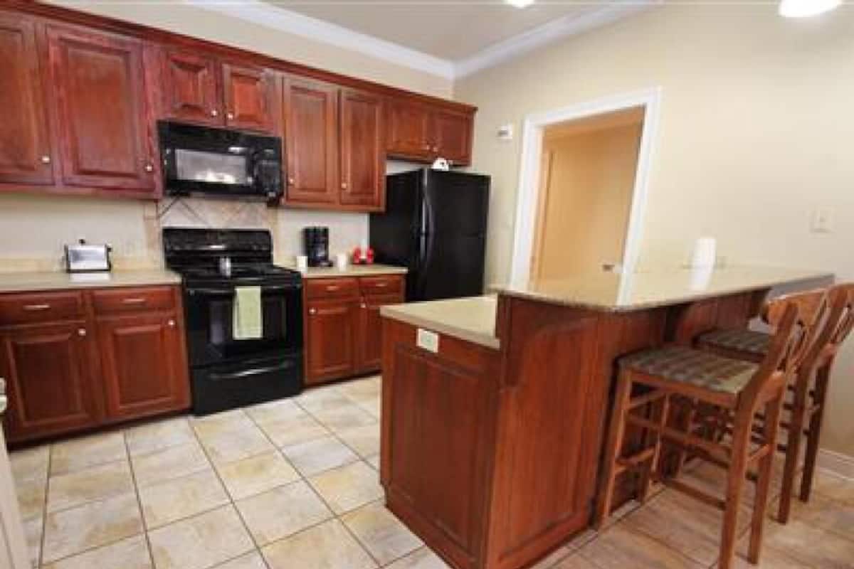 A kitchen with wooden cabinets, a black refrigerator, a stove, and a microwave.
