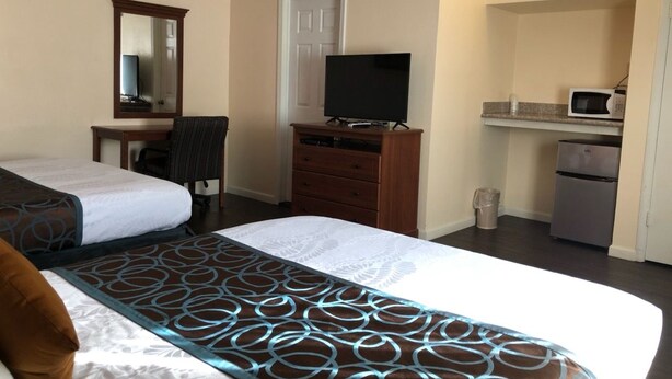 A hotel room with two beds, a desk with a TV, a refrigerator, and a microwave. - Turtle Bay Lodge (Redding)