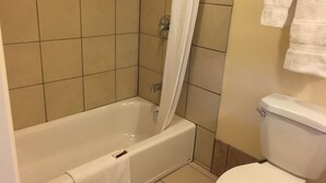 A bathroom with a bathtub, toilet, and tiled walls. - Turtle Bay Lodge (Redding)