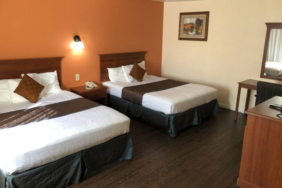 Hotellihuone, jossa on kaksi sänkyä, työpöytä ja yöpöytä.