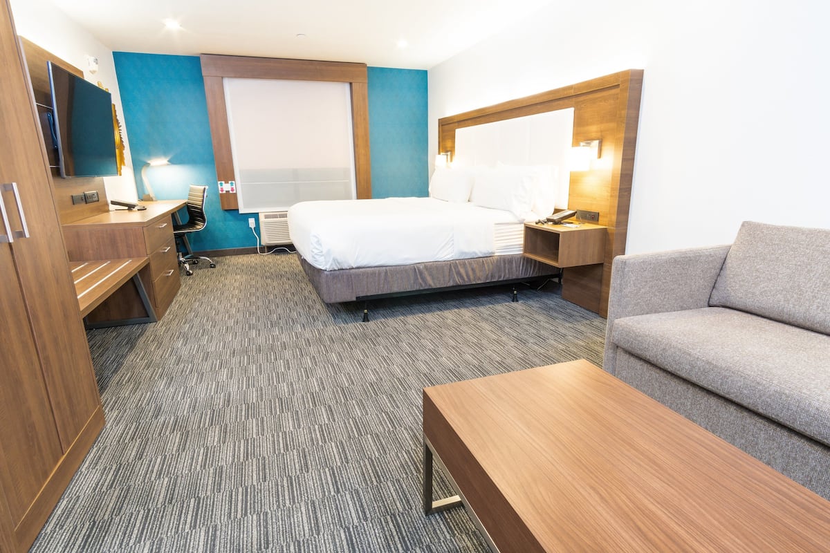 Une chambre d’hôtel équipée d’un lit, d’un bureau, d’une chaise, d’un canapé et d’une télévision.