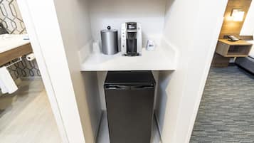 Una kitchenette compacta con cafetera, hervidor y un bote de basura.