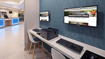 Una moderna recepción de hotel con una computadora, impresora y un monitor de pantalla plana mostrando un sitio web.