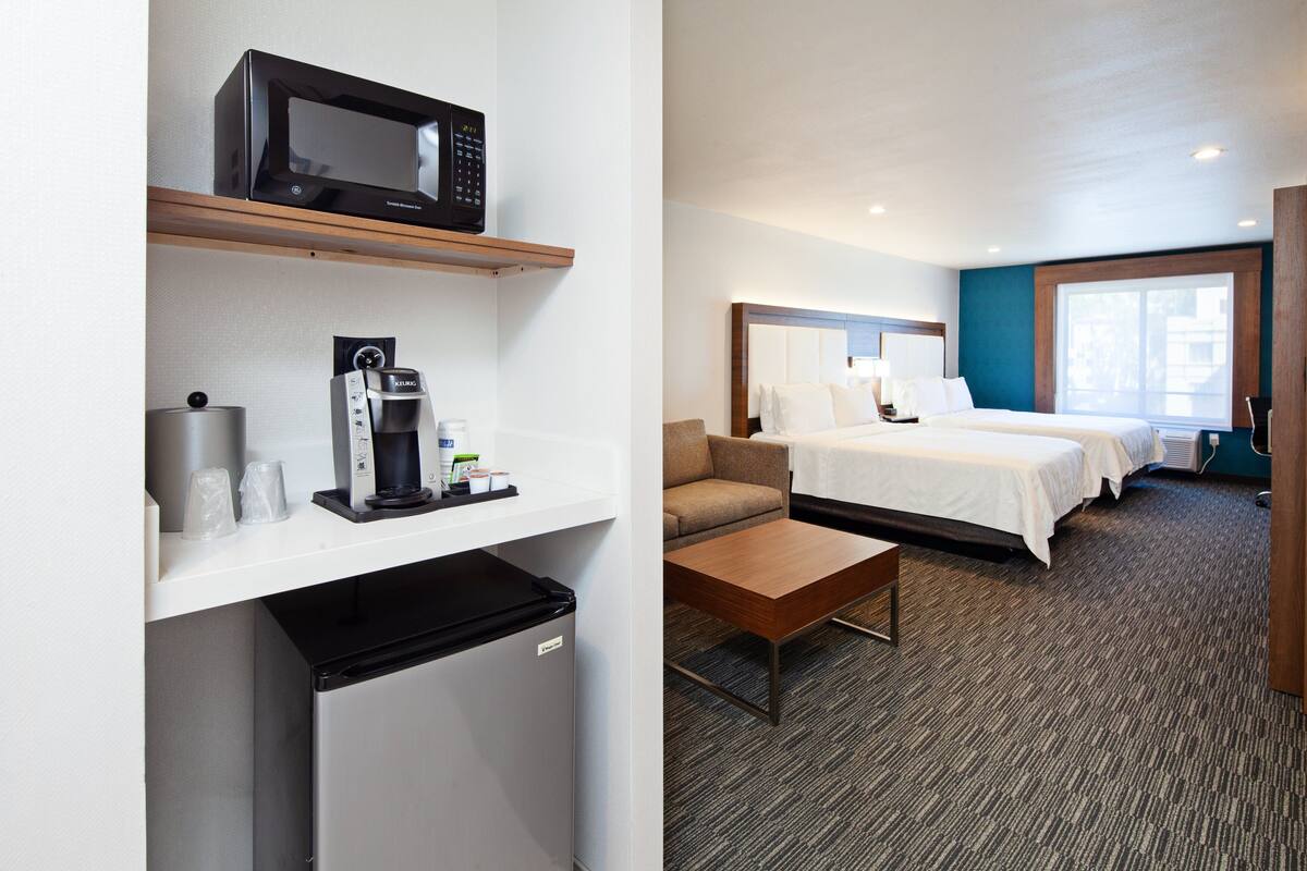 Une chambre d’hôtel avec une kitchenette, un lit, un canapé et une fenêtre.