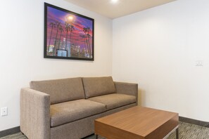 A modern room with a beige sofa, a wooden coffee table, and a framed cityscape picture on the wall.