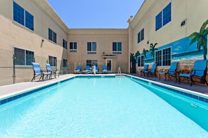 A swimming pool with lounge chairs and a mural of a beach scene.