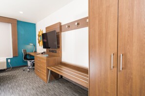 A modern hotel room with a wooden desk, a flat-screen TV, a chair, and a wardrobe. - Holiday Inn Express Hotel & Suites Hollywood Walk of Fame by IHG (Los Angeles)