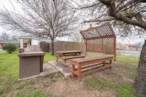 A backyard with a barbecue grill, picnic table, and bench. - OYO Hotel San Antonio Near At&t Center (San Antonio)