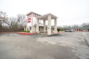 A motel with a central entrance, a parking lot, and a row of rooms in the background. - OYO Hotel San Antonio Near At&t Center (San Antonio)