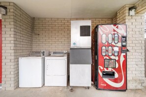 A laundromat with a vending machine, a dryer, and a washing machine. - OYO Hotel San Antonio Near At&t Center (San Antonio)