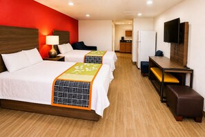 Ein Hotelzimmer mit zwei Betten, einem Schreibtisch, einem Fernseher und einer Küchenzeile.