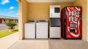 A laundromat with two washers, a dryer, and a Coca-Cola vending machine. - OYO Hotel San Antonio Near At&t Center (San Antonio)