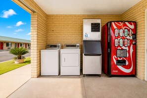 Eine Wascherei mit zwei Waschmaschinen, einem Trockner und einer Coca-Cola-Getränkeautomaten.