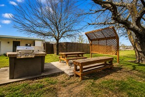 An outdoor patio area with a grill, picnic tables, and a wooden pergola. - OYO Hotel San Antonio Near At&t Center (San Antonio)