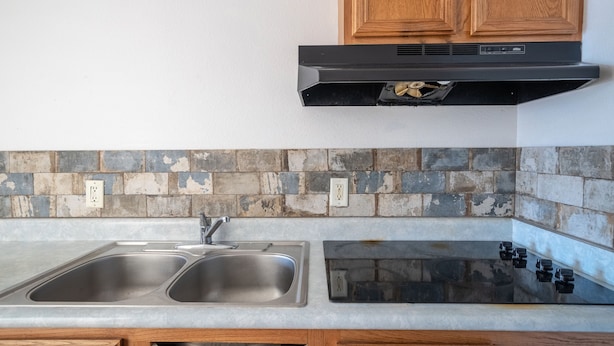 A kitchen with a double sink, a stove, and wooden cabinets.
